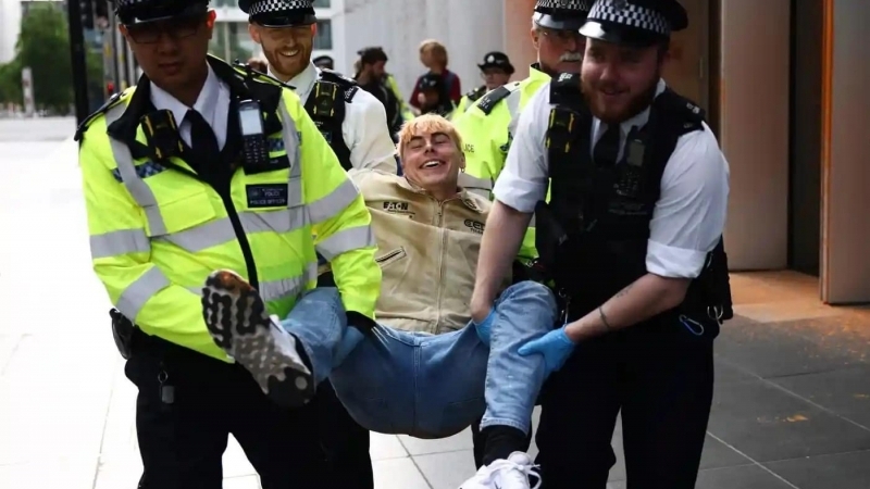 Fotografia dimineții - Un activist de mediu este reținut de polițiștii englezi după ce a aruncat cu vopsea portocalie asupra sediului TotalEnergies din Londra